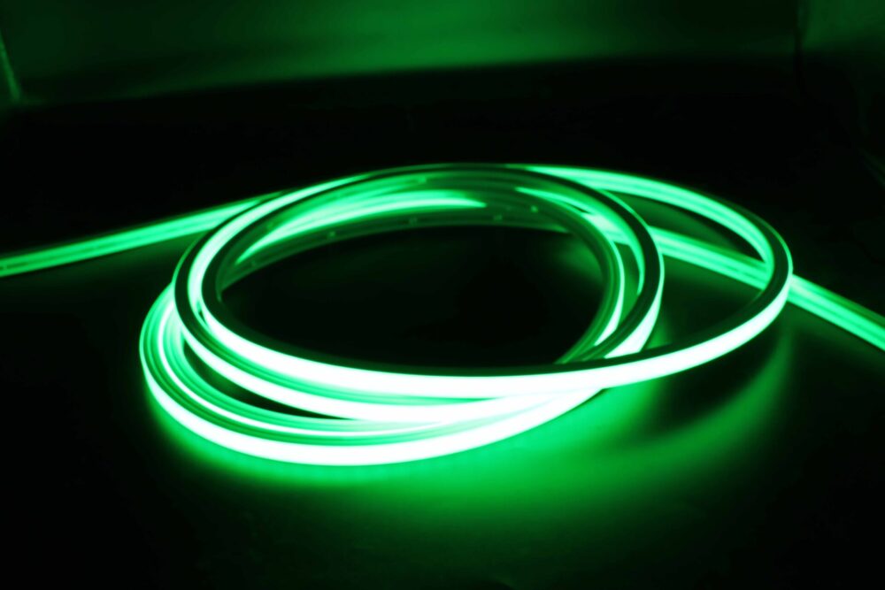 Green illuminated neon flex LED strip coiled in dark environment